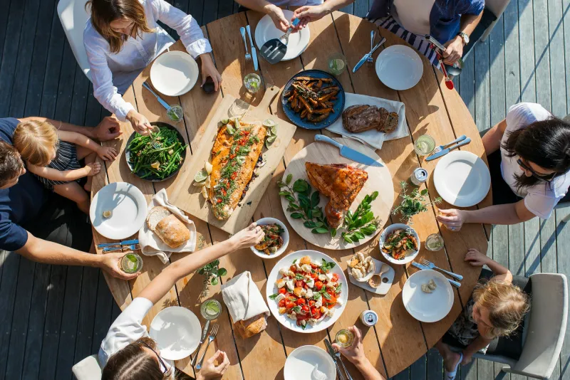 Friends sharing dishes around a long wooden table